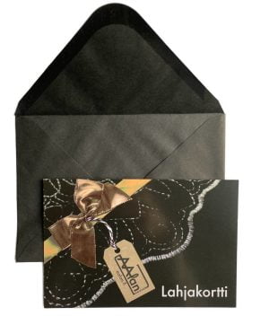 Mustan avonaisen kirjekuoren päällä mustapohjainen lahjakortti, jossa kuva pistimäisestä brodeeratusta kuviosta ja pronssinvärisestä lahjanauhasta.