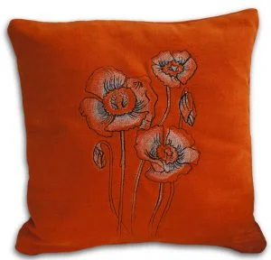 Oranssi pehmeäpintainen tyyny, jossa brodeerattu keveän läpikuultava Unikot-kuvio.
