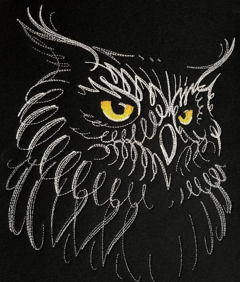 Lähikuva konekirjotusta kalligrafisesta pöllöstä mustalla villahuovalla