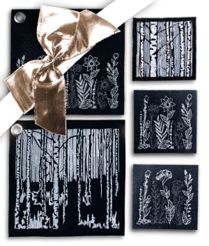 Kokoelma mustasta huovasta valmistettuja pannulappuja ja lasinalusia, joissa kauniit konekirjotut koivu- sekä kukkakuvioinnit valkoisella ja harmaalla