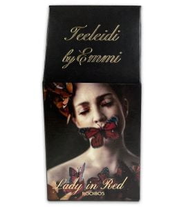 Musta paketti Teeleidin Lady in Red -rooibosta. Paketissa kuva kauniista naisesta punaisten perhosten ympäröimänä.