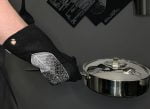 Mustasta huovasta valmistettu Lehti-patakinnas miehen kädessä, joka pitelee paistinpannua