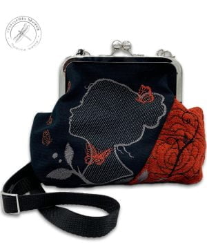 A handcrafted Frame Purse from coppery red upholstery remnant fabric accompanied with black cotton fabric. Machine embroidered beautiful woman's silhoutte.