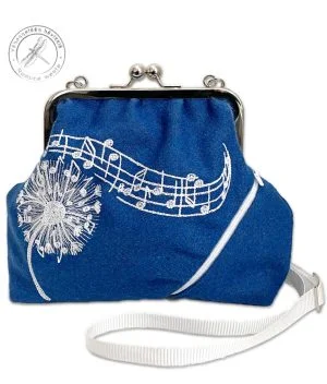 Blue purse handcrafted form remnant woolfabric, with a machine embroidered fluffy dandelion on white rayon thread. White notes flying from the flower as the fluff seeds in the wind. On the front part of the purse a small zip pocket. In the upper corner of the picture a stamp-like round mark indicating the Dragonfly Collection, where the text in finnish and english: ” Reduce waste.”   
