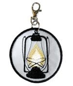 Handcrafted round reflective pendant. The handdrawn Hurricane lantern is machine embroidered with black rayon thread.