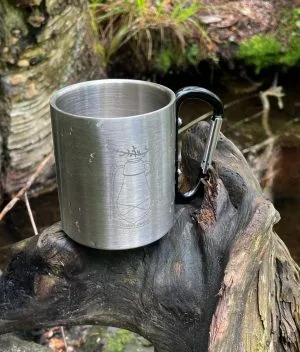 Metallinen Lyhty-muki purossa olevan juurakon päällä.