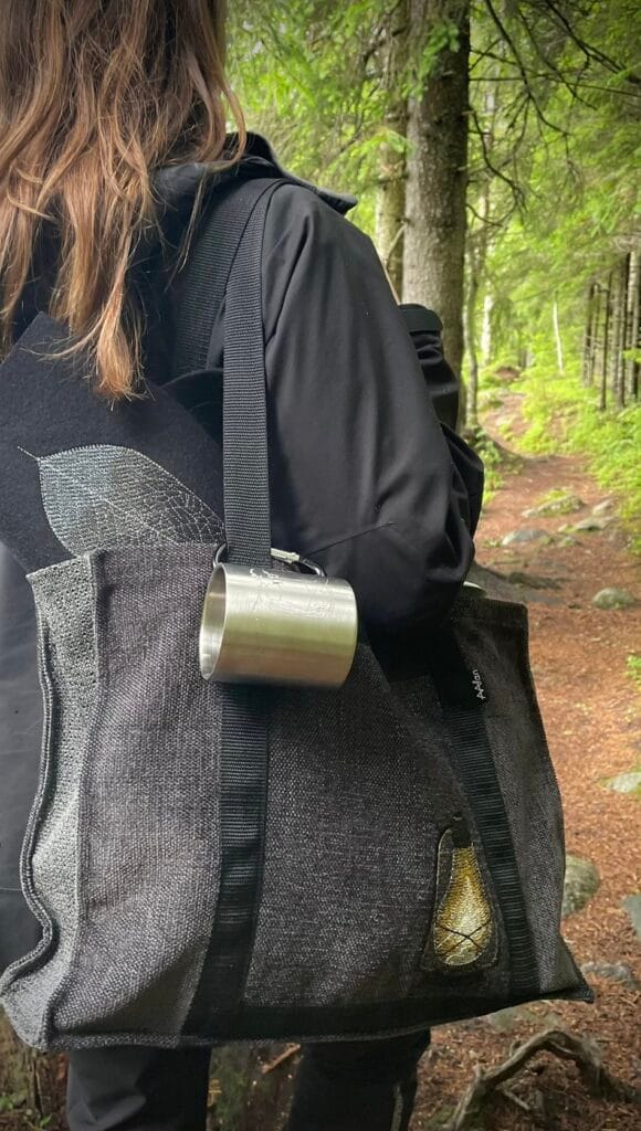Metsäpolku, jolla juuria ja kiviä. Nainen etualalla selkä kameraan päin, kulkemassa polkua.